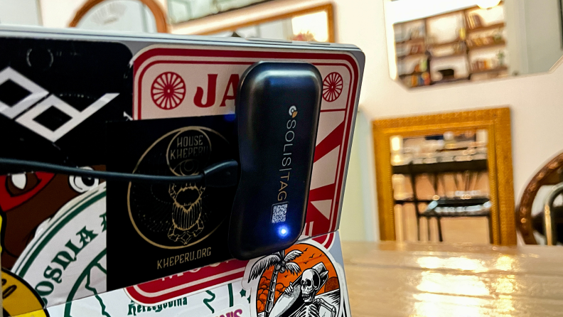 The Simo Solis Tag attached to the back of a laptop with many sticker designs.