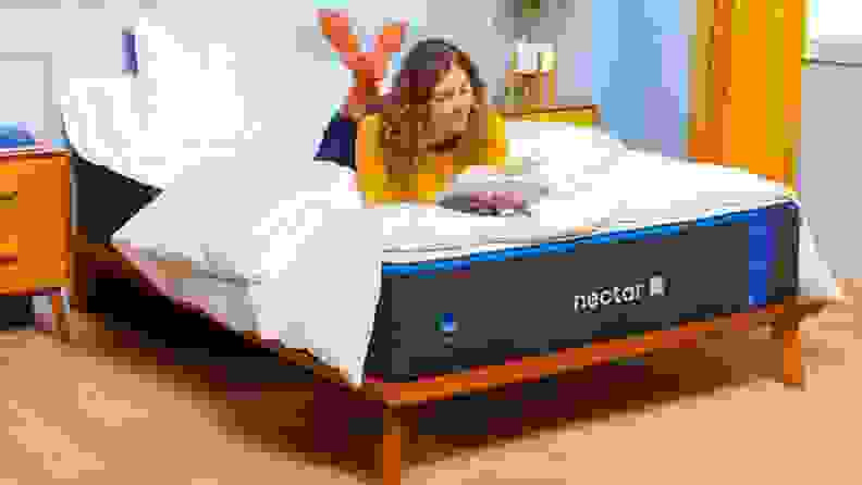 a person lies on the Nectar mattress reading a book