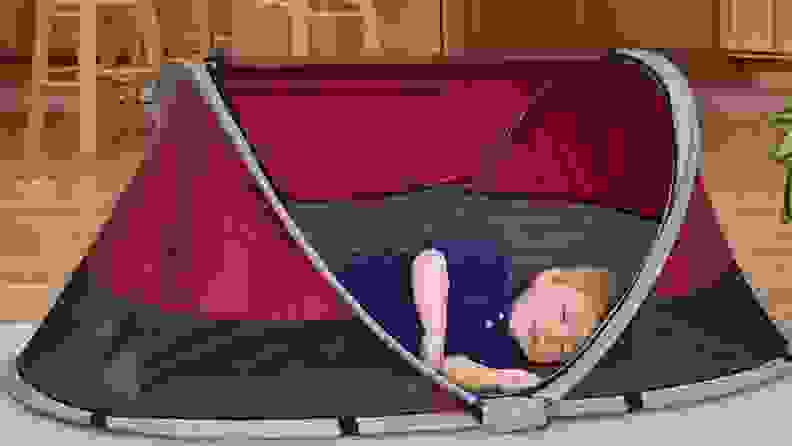 A toddler boy sleeps in his red KidCo Peapod
