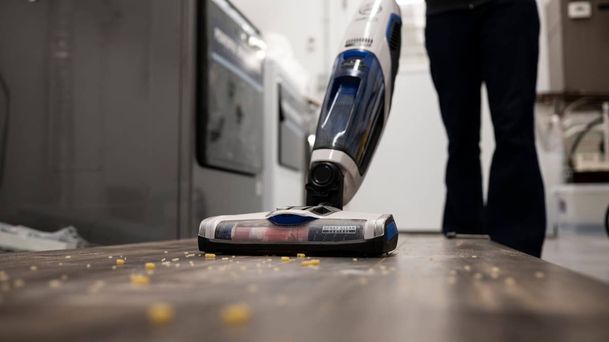 Someone in black pants vacuums raw pasta off a bare floor