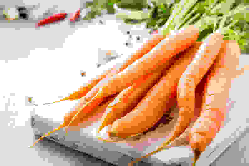 Carrots with vegetarian cooking ingredients. Bio healthy food concept. Organic vegetables on old wooden cutting board. Copy space.