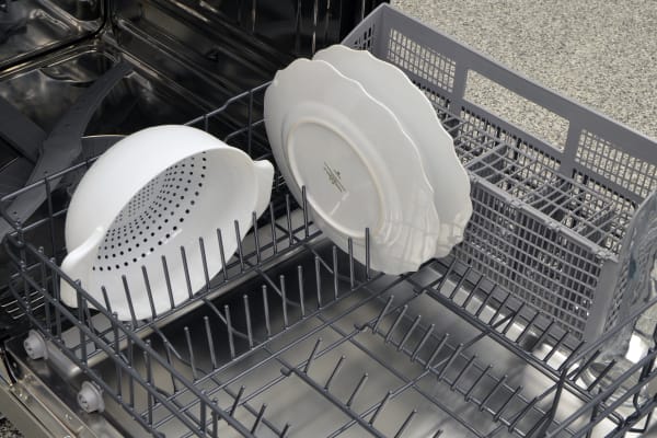 A colander and some thick plates loaded in the lower rack
