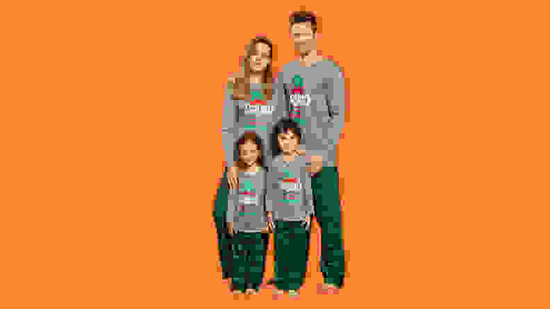 A family wearing the PatPat Elf Squad matching family Christmas pajamas on an orange background.
