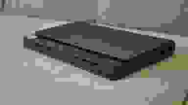 The folded, all-black ThinkPad computer sits on a plush grey cushion like a ledger.