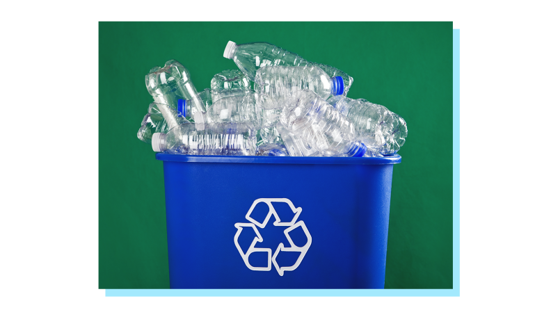 Plastic water bottles piled up inside of blue recycling bin.