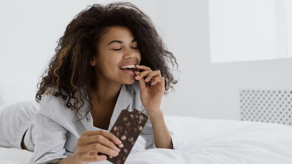 Woman eating milk chocolate in bed