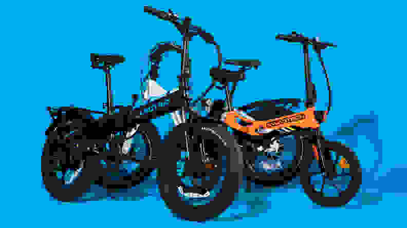 A group of folding electric bikes sit against a blue backdrop.