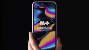 Hand holding phone with colorful Gabb Music+ logo on screen