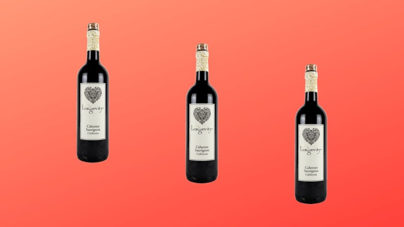 Tres botellas de vino Longevity Cabernet Sauvignon se colocan sobre un fondo degradado rojo.