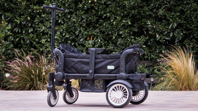 A joey stroller outside in front of a hedge.