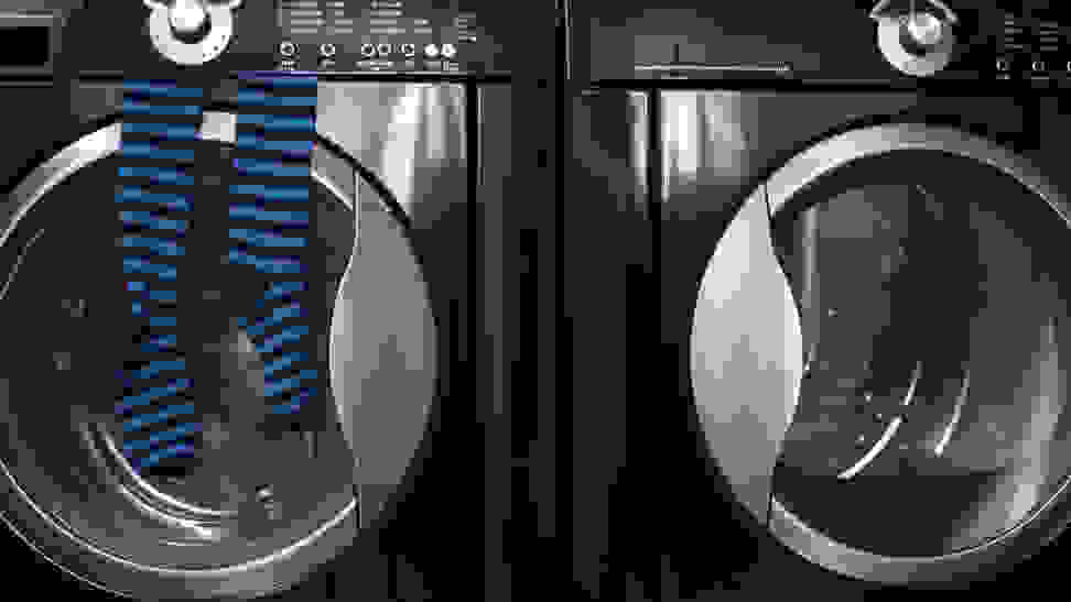 A close-up of a dark navy blue washer and dryer pair. A pair of blue and black striped socks hang from the door of the washer.