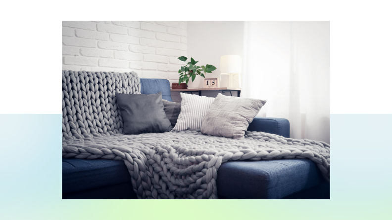 A gray throw blanket covers a stylish blue sofa.
