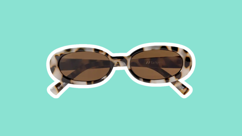 The Le Specs Outta Love Oval-Frame Tortoiseshell Acetate Sunglasses on a green background.