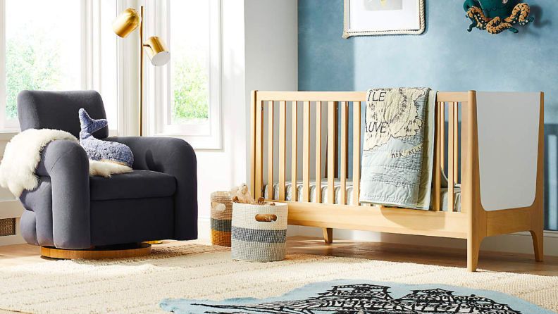 A gray rocking chair next to a crib.