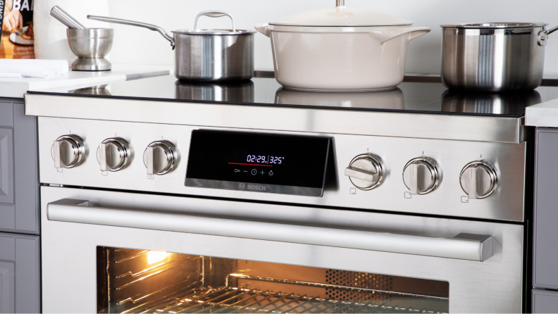The Bosch HIS8655U 36-in Induction Range shot up close, with cookware on top and the oven light on