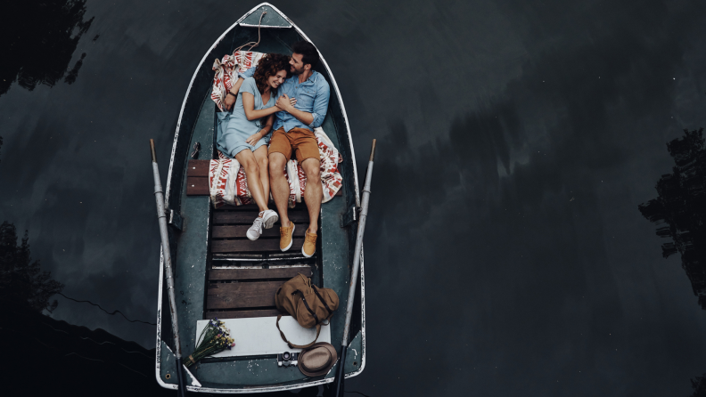 A couple lounges in a rowboat together.