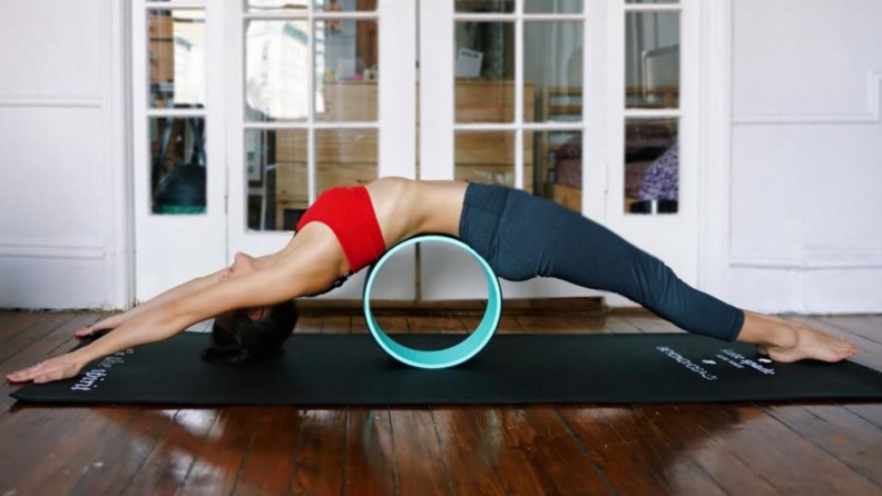 A yogi works out with the help of a yoga wheel.
