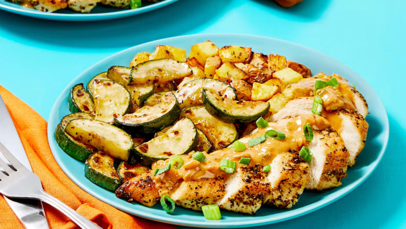 A plate of Creamy Dijon Chicken from EveryPlate on a colored surface.