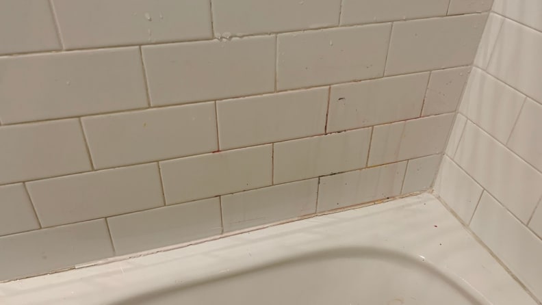 The grout on a bathroom wall is stained with crayon.