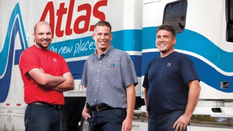 Three men standing and a hauling truck behind them
