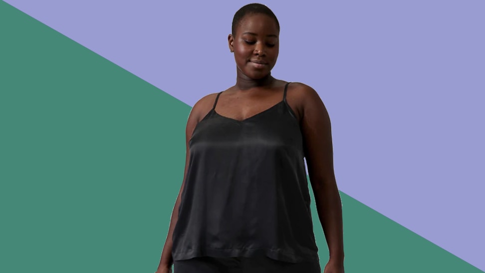 An image of a woman in a black silky cami top on a green and purple background.