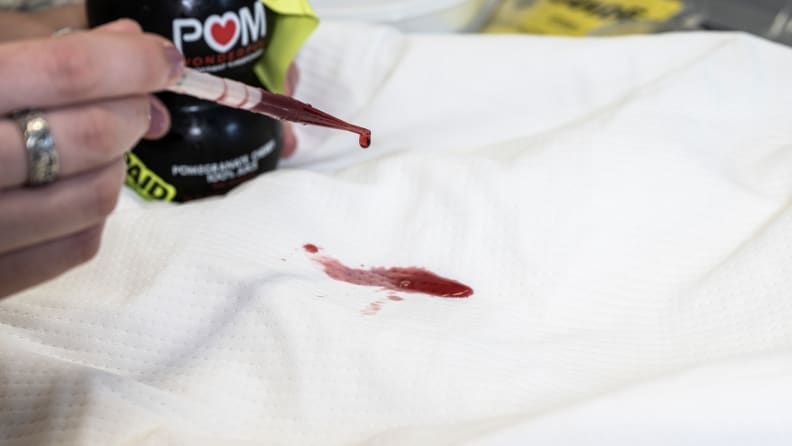 una pipetta riempita di succo di melograno rosso fa cadere il liquido su un proteggi-materasso