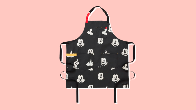 A black apron with a repeated pattern of Mickey Mouse's face.