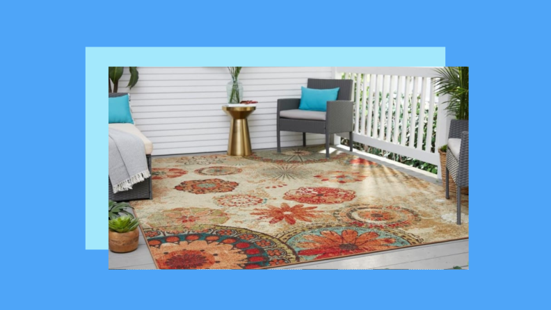 A boho floral rug on a patio against a blue background.