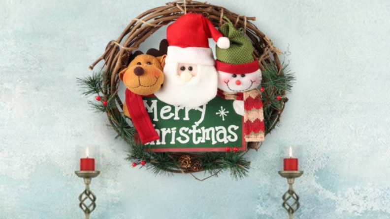 Plush wreath with a reindeer, snowman, and Santa Claus with a message reading "Merry Christmas" hanging on a mantle