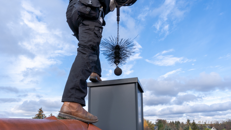 Chimney cleaner using tool to clear out chimney.