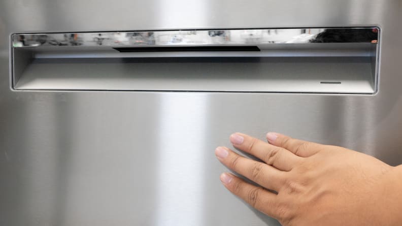A person touching the outside of the Bosch 800 Series dishwasher.