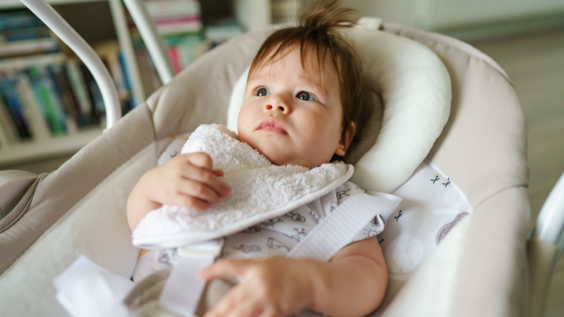 Small baby laying swing while staring upwards.