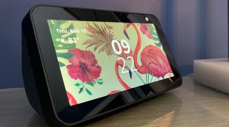 Amazon's Echo Show 5, an Alexa-enabled smart display, sits on a table displaying the time.