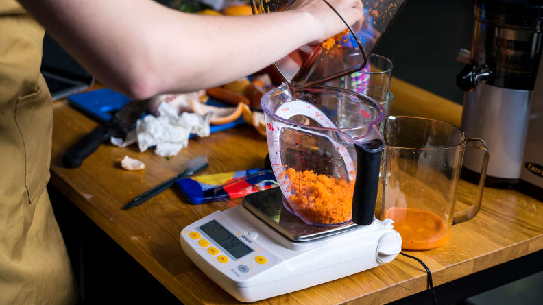 Measuring carrot pulp in a measuring cup for juicers