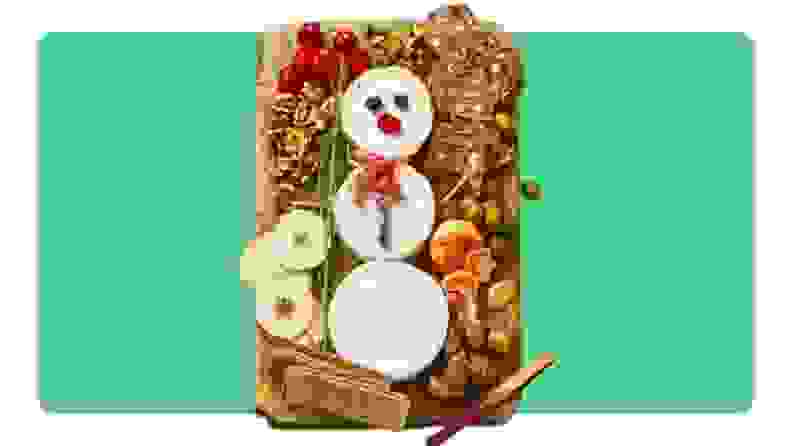 A cutting board with snacks making up a snowman.