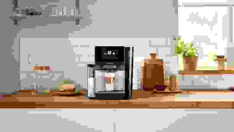 Bosch espresso machine with a prepared latte at the base, shot in a kitchen setting