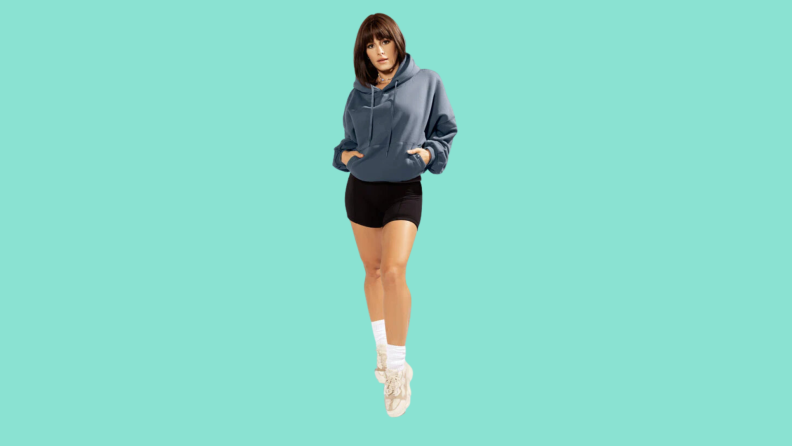 A model wearing a blue hoodie and black shorts.