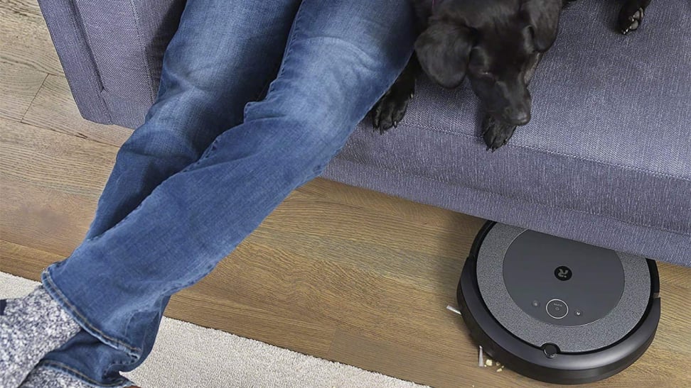 Man on couch with dog. Robot vacuum under couch.