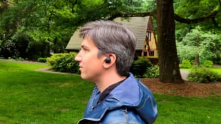 A handsome man wearing a pair of true wireless earbuds amongst the majesty of nature