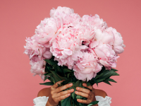 Woman holding bouquet of pink flowers in front of her face