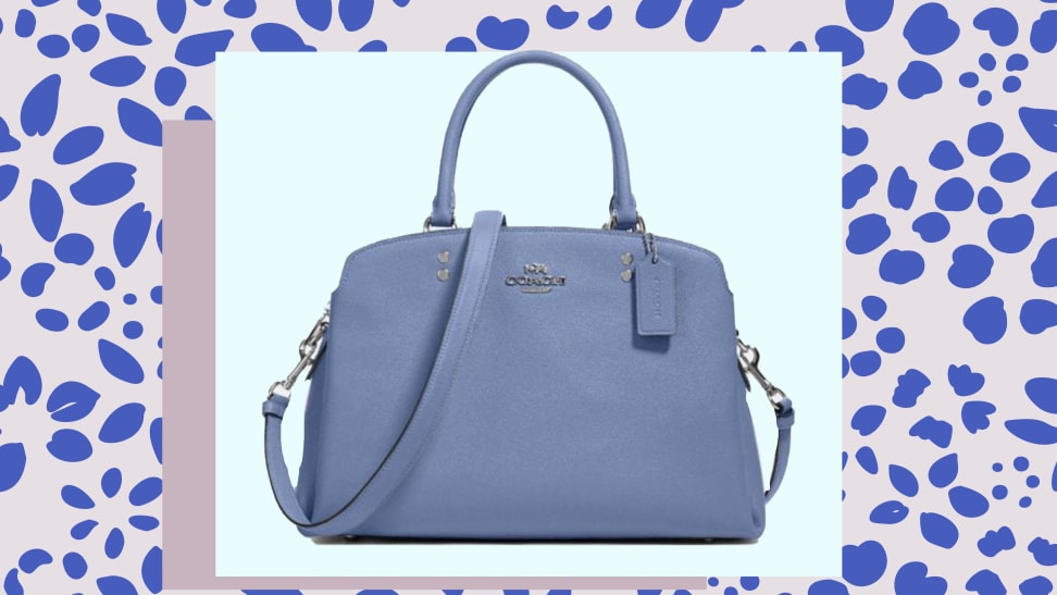 A blue leather cross body Coach bag, against a blue patterned background.
