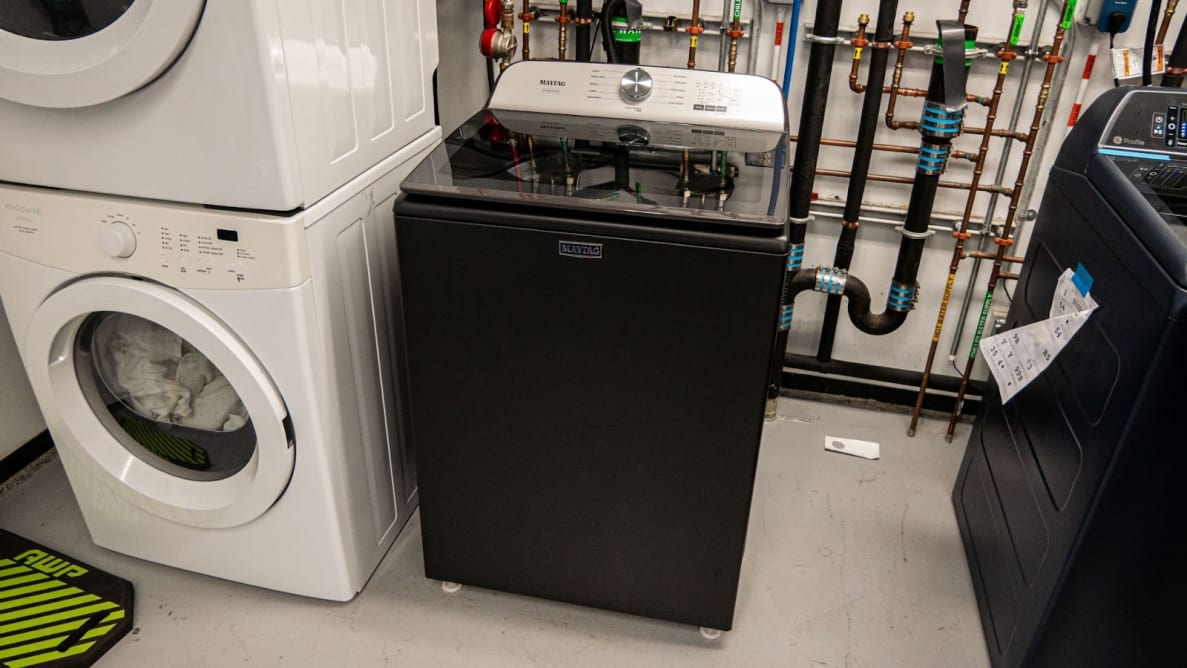 Black and silver Maytag MVW6500MBK top-loading washer inside of testing lab indoors.