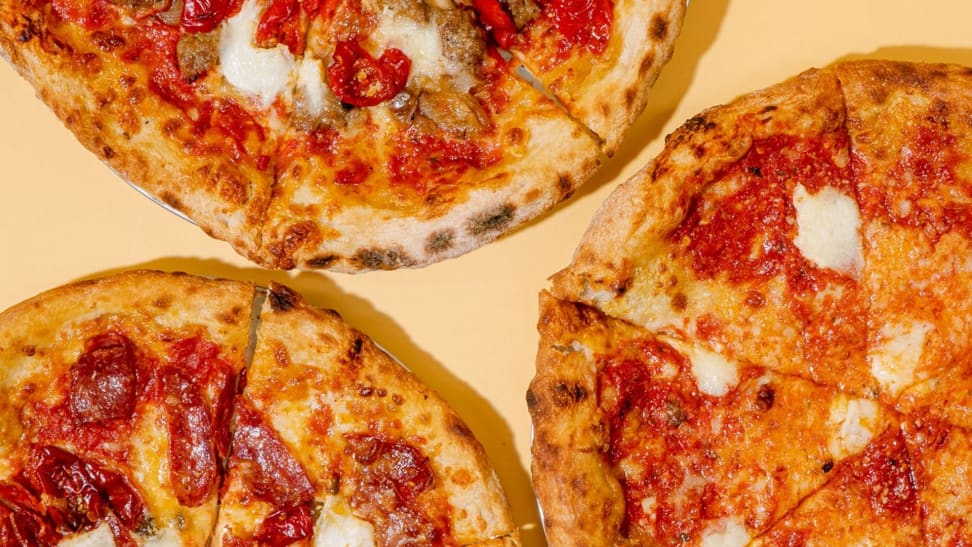 An overhead photo of three wood-fired pizzas, one cheese, one pepperoni, and one sausage and peppers.