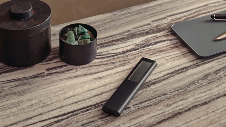 Samsung's solar-charging Eco Remote is pictured on a tabletop beside some decorative crystals and an ink pen.