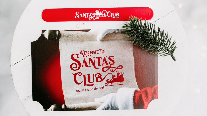 A pair of hands with white gloves holding an invitation to Santa's Club that shows an image of a red sleigh.