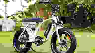 Photo of a white Addmotor electric bike parked in the grass.