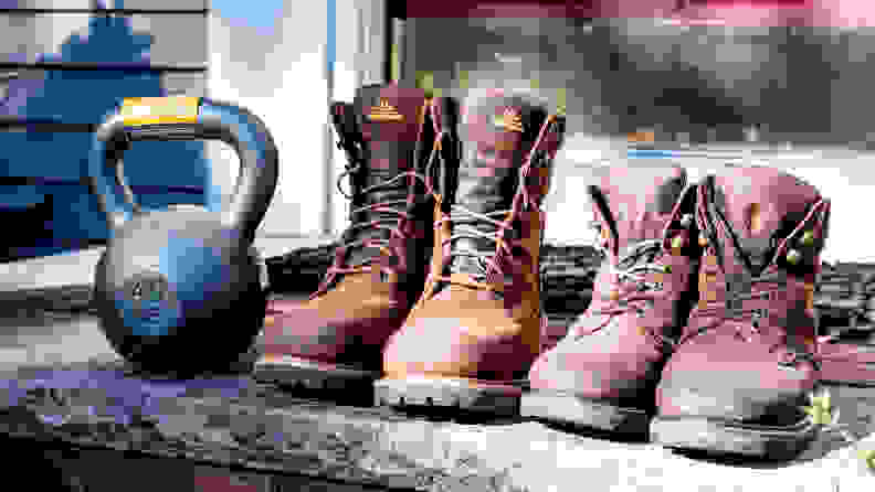 Two pairs of work boots are lined up next to a kettle weight.