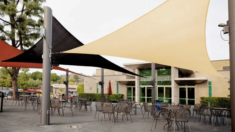 Cafe patio covered by three shade sails, connected to poles