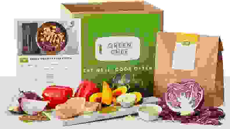 Green Chef box with recipe card and raw ingredients on a board, including red onion, bell pepper, pork chops, acorn squash, and purple cabbage.