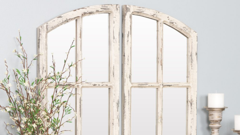 Distressed white wood windowpane on a gray wall next to a plant